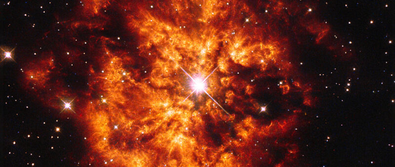 An orange nebula surrounds a bright white star.