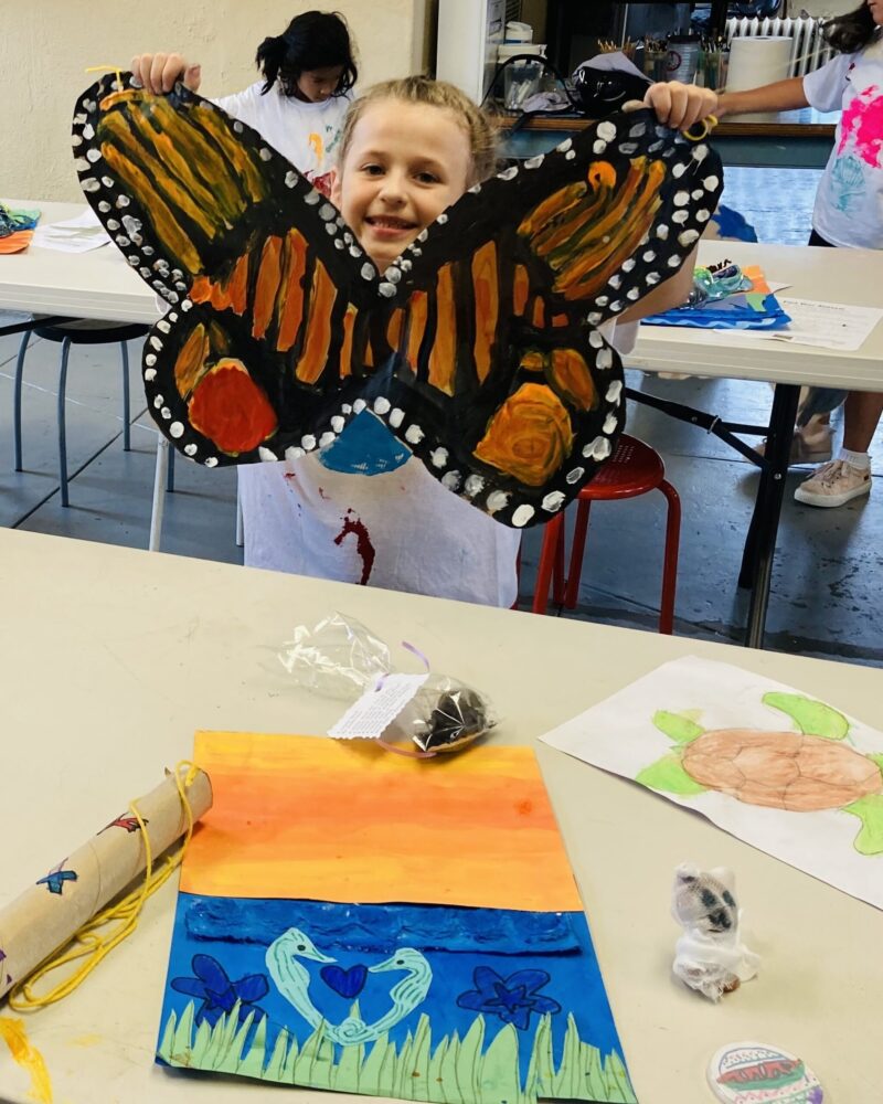 A Junior Explorer proudly displays a butterfly model she created.